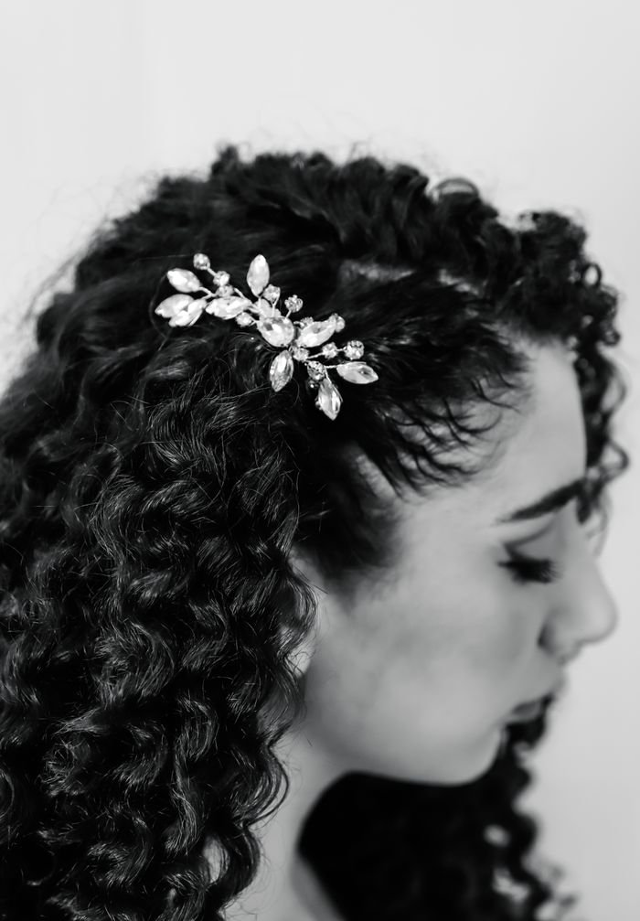 Black and white portrait of a woman with curly hair and decorative hairpin.