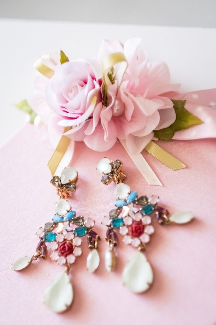 Beautiful floral earrings and pink rose arrangement on soft pink background, perfect for gifts.